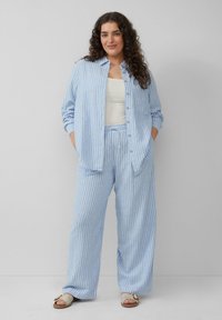 Lichtblauw gestreept shirt en bijpassende wijde broek van zachte stof. Knoopsluiting ontwerp met een relaxte pasvorm en een elastische tailleband.