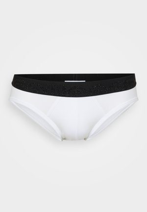 Weiße Unterhosen mit einem schwarzen elastischen Bund, der ein strukturiertes Logo-Muster aufweist. Glattes Material, mittelhohe Passform und nahtlose Seiten.