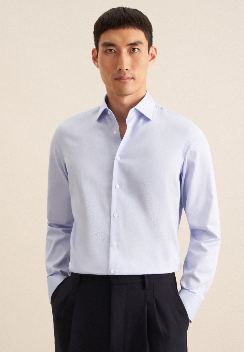 Lichtblauw overhemd met een spread collar, lange mouwen en subtiele textuur. Draag het met donkere op maat gemaakte broek, die een getailleerd ontwerp laat zien.