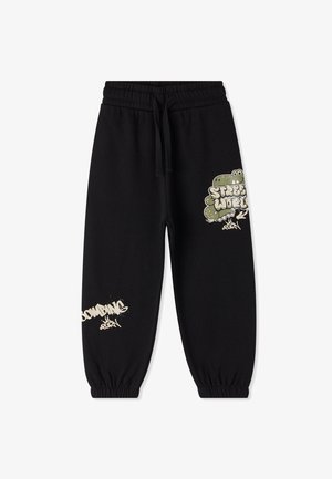 Pantaloni tuta neri in cotone, con stampe in stile graffiti verdi e bianche, polsini elasticizzati e vita regolabile con cordino.