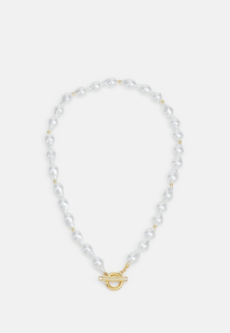 Collier avec des perles blanches irrégulières et de petites perles dorées, doté d'un fermoir doré de type toggle à l'avant, présenté sur un fond uni.