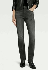 Svarte denimjeans med smal passform, høy midje og frontlommer. Glatt tekstur med et subtilt falmet mønster. Kombinert med ankelstøvler.