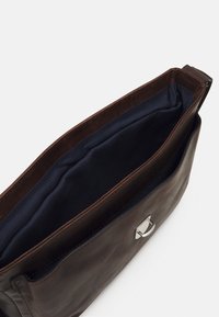 Borsa in pelle marrone con una texture liscia, hardware in argento e interno in tessuto blu. Design aperto che consente un facile accesso ai contenuti.