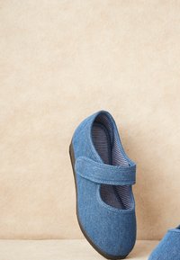 Zapatos de tela azul con un diseño tipo Mary Jane, cuentan con una tira de velcro, un forro interior a rayas y una suela de goma negra.