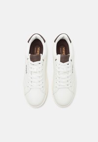 Baltas sporta apavi ar gludu ādas virsmu, brūniem akcentiem uz papēža un mēles, kā arī plakanām šņorēm. Atmiņas putu zolītes komfortam.