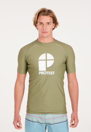Olijfgroene rash guard met korte mouwen en een wit "PROTEST" logo aan de voorkant. Een paar gestreepte zwemshorts zichtbaar eronder. Glad, rekbaar materiaal.