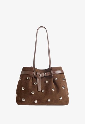Sac à main en daim marron avec de longues lanières en cuir, une ceinture à boucle frontale et des clous ronds argentés espacés régulièrement sur le corps.