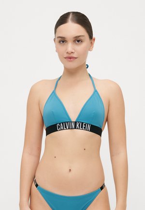 Tee groene driehoek bikini top met een zwarte tailleband met het "CALVIN KLEIN" logo. Het materiaal is glad met een aansluitend ontwerp en minimale hardware.
