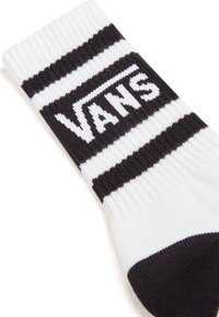 Hvid sok med sorte striber, ribbet tekstur og et fremtrædende Vans-logo i fed hvid skrift på en sort baggrund.