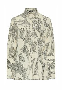 Collared long-sleeve shirt in cream with black abstract pattern, featuring a button front and slightly loose fit. Fabric has a smooth texture.
