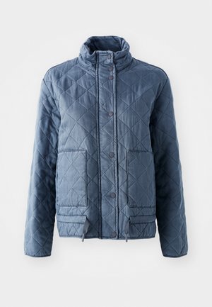 Corta-mato acolchoado em azul-escuro, com colarinho elevado, botões e dois bolsos frontais. Tecido suave com uma aparência texturizada e isolante.