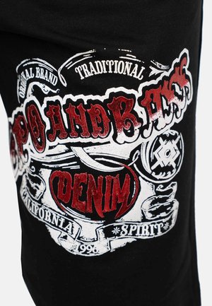 Schwarzes T-Shirt mit einem mehrfarbigen Grafikdruck, der Text und Designs enthält, darunter "Denim" und dekorative Verzierungen.