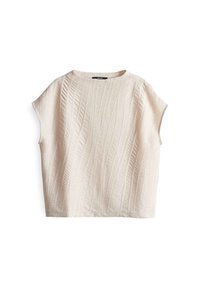 Top a maniche corte di colore crema con un motivo texturizzato e ondulato, dalla vestibilità ampia, con scollatura rotonda e senza chiusure visibili.