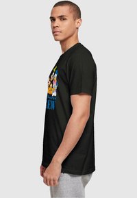 Camiseta negra de algodón con un gráfico colorido de personajes de dibujos animados y el texto "Disney Crew" en azul, sobre un fondo liso.