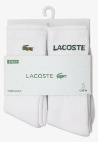 Chaussettes blanches mi-hautes en lot de 6, avec logo Lacoste vert et broderie de crocodile. Tissu côtelé texturé avec soutien rembourré.