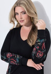 Czarna sukienka z długim rękawem i dekoltem w serek, zdobiona kolorowymi wzorami róż na rękawach. Gładka tkanina o dopasowanym kroju.