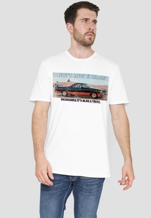 White cotton t-shirt featuring a graphic print of a Chevy El Camino with text. Short sleeves, crew neck, relaxed fit.