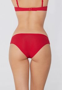 Rotes Bikini-Set aus glattem Stoff. Der Oberteil verfügt über dünne, verstellbare Träger, während der Unterteil einen modischen Schnitt mit nahtlosem Finish hat.