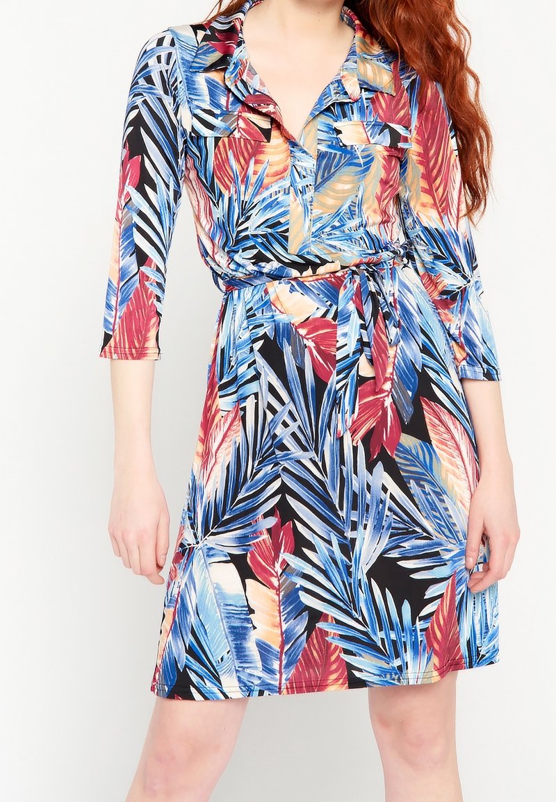 Robe à manches courtes avec un motif vibrant de feuilles tropicales en bleu, rouge et jaune sur un fond noir ; taille cintrée avec ceinture assortie.