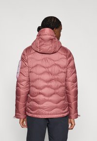 Μπουφάν με επένδυση σε απαλό ροζ χρώμα με κυματιστό σχέδιο ραφής, ελαστικά μανσέτες και στενή κουκούλα, με μοβ λεπτομέρεια στον ένα μανίκι.