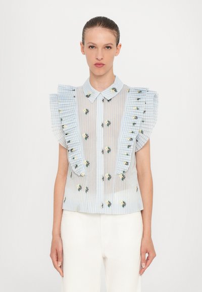 Blouse rayée bleu et blanc avec de grandes manches à volants, broderie florale et boutonnière à l'avant. Tissu léger et semi-transparent.