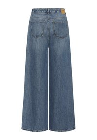 Zadnji pogled na široke modre jeans hlače z dvema zadnjima žepoma in usnjeno znamko na pasu.