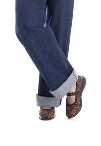 Jeans de denim azul con los puños doblados, combinados con bailarinas de estampado de leopardo marrón que tienen una suela de goma negra y una correa en el empeine.