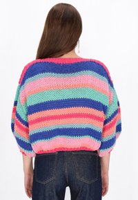 Vzorovaný pletený svetr s mnoha barvami v živých odstínech růžové, modré, zelené a fialové; oversized střih s balónovými rukávy.