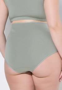 Zelené bezešvé kalhotky s vysokým pasem, hladkým povrchem a decentním leskem, s širokým pasem pro pohodlí a zakrytí.