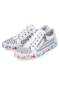 White sneakers featuring intricate cut-out patterns, a side zipper, and a multicolored floral print rubber sole. Smooth texture throughout.