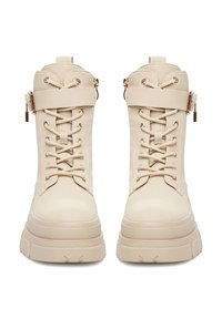 Beżowe buty sznurowane z teksturowanym wykończeniem, złotymi akcentami i zamkiem błyskawicznym po boku, zaokrąglonym noskiem i grubą podeszwą.