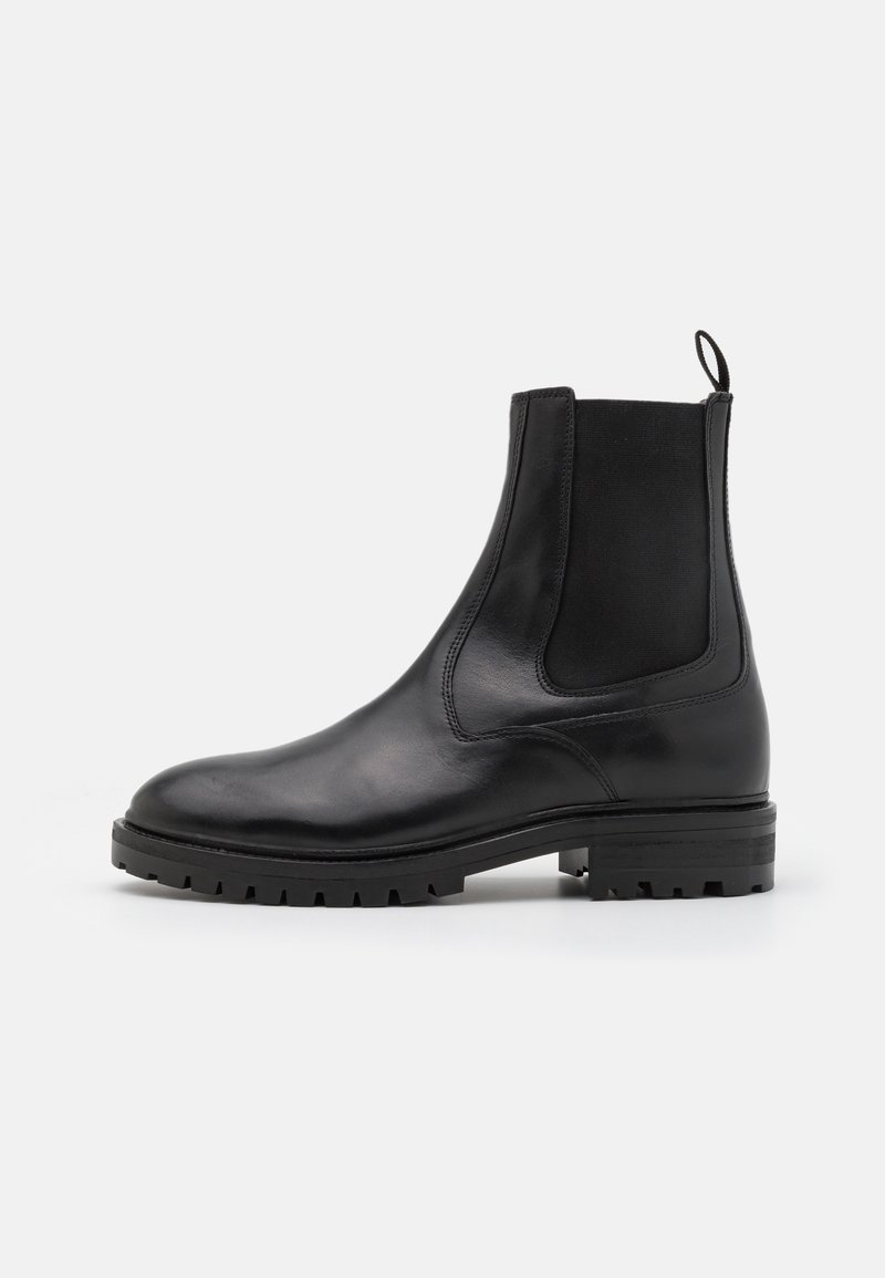 Bottes Chelsea en cuir noir avec des panneaux élastiques sur les côtés, bout rond et semelle en caoutchouc texturé ; elles disposent d'une languette pour un enfilage facile.