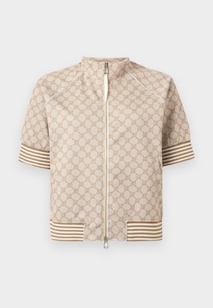 Beige kortermet jakke med frontglidelås, geometrisk mønster og brune og hvite stripete mansjetter og kant.