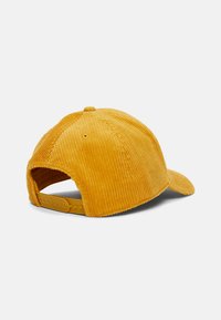 Gorra de pana amarilla con visera curvada, correa de plástico ajustable en la parte posterior y crestas texturizadas en la tela.