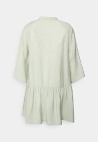 Vestido tunica verde-claro com colarinho, mangas três quartos e cintura franzida para uma silhueta rodada. Tecido suave e texturizado.