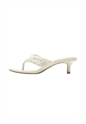 Sandale blanche à bout ouvert avec bride entre les orteils ornée d'embellissements ronds et talon fin de hauteur moyenne.