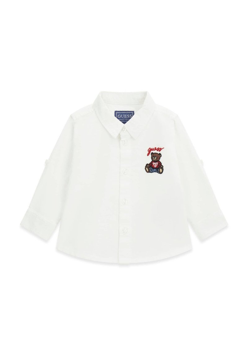 Camicia bianca a maniche lunghe con colletto button-down, caratterizzata da un orso ricamato e testo "guess" sul petto sinistro. Tessuto di cotone liscio.