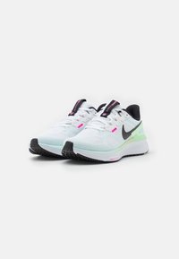 Une paire de chaussures de course Nike blanche et vert menthe clair avec un swoosh noir, des détails roses et des semelles noires sur un fond blanc uni.