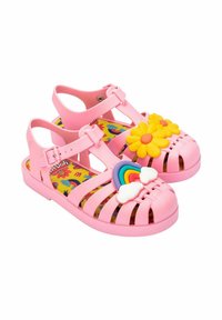 Sandalias de plástico rosa con diseño perforado, que presentan un adorno de flor amarilla y nubes en arcoíris. Interior con estampado floral colorido.