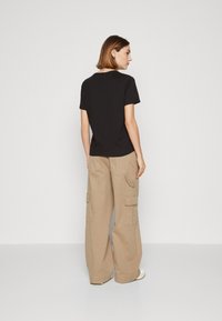 Svart t-skjorte med kortermet, laget av bomull, kombinert med beige cargo-bukser med sidelommer og avslappet passform.