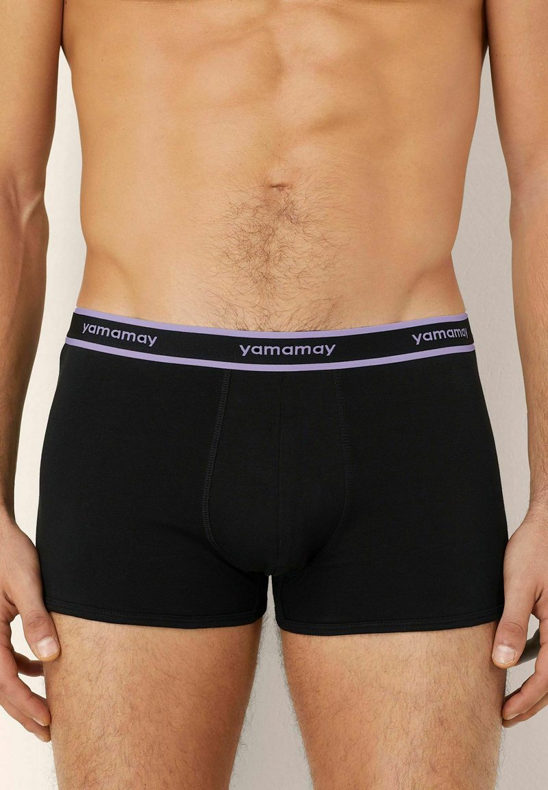 Boxeri scurți din bumbac negru cu un brâu contrastant de culoare mov, pe care este inscripționat textul "yamamay", oferind un design ajustat și o textură netedă.