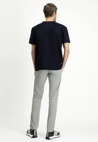 Camicia a maniche corte blu navy abbinata a pantaloni grigio chiaro. L'outfit presenta una vestibilità rilassata, una texture liscia e dettagli di cucitura sottili.