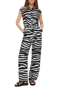 Combinaison à motifs zèbre en noir et blanc, avec un col, des manches courtes, une taille ceinturée et une coupe ample avec des poches latérales.