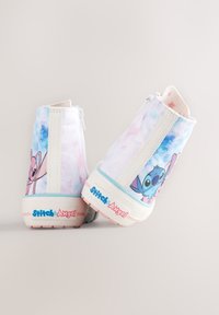 Baskets montantes avec une tige tie-dye pastel présentant des graphiques Stitch et Angel, fermeture éclair blanche, et le logo "Stitch & Angel" sur la semelle.