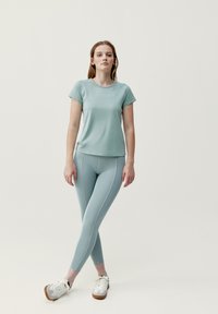 Lichtblauwe sportset bestaande uit een T-shirt met korte mouwen en legging met contrasterende stiksels. De leggings zijn aansluitend en strakker.