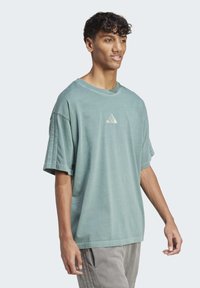 Světle zelené oversize bavlněné tričko s kulatým výstřihem, na hrudi s malým bílým logem Adidas a krátkými rukávy.