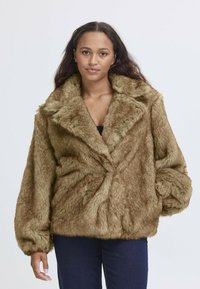 Cappotto in pelliccia sintetica marrone con un ampio colletto, vestibilità over e texture soffice. Presenta un design avvolgente e maniche arricciate.