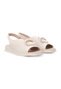 Beige offene Sandalen mit durchlöchertem Design und goldenen, runden Akzenten, ausgestattet mit einem verstellbaren Fersenriemen und flacher Sohle.
