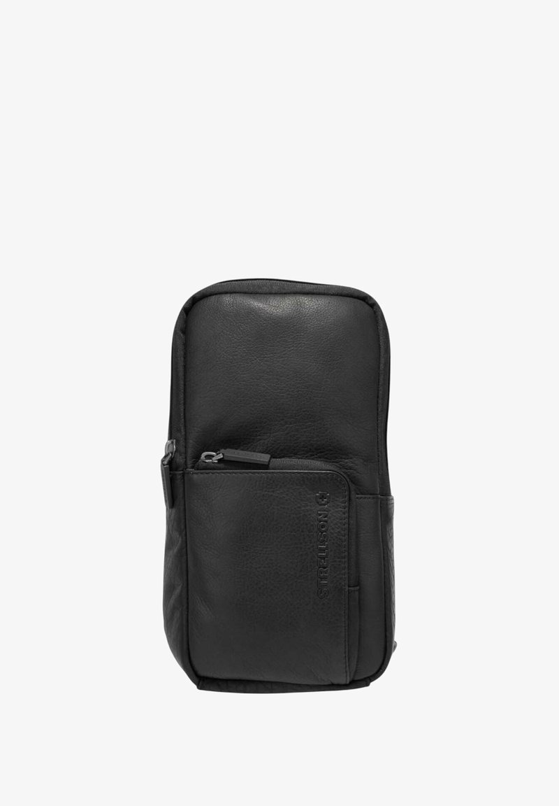 Mochila de cuero negro con textura suave, cuenta con un bolsillo con cremallera en la parte frontal y un logo en relieve. Diseño compacto con bordes redondeados.
