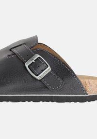Sort lædersandal med struktureret finish, justerbar sølvmetal spænde, korkfodbed og en kontrasterende hvid gummisål.
